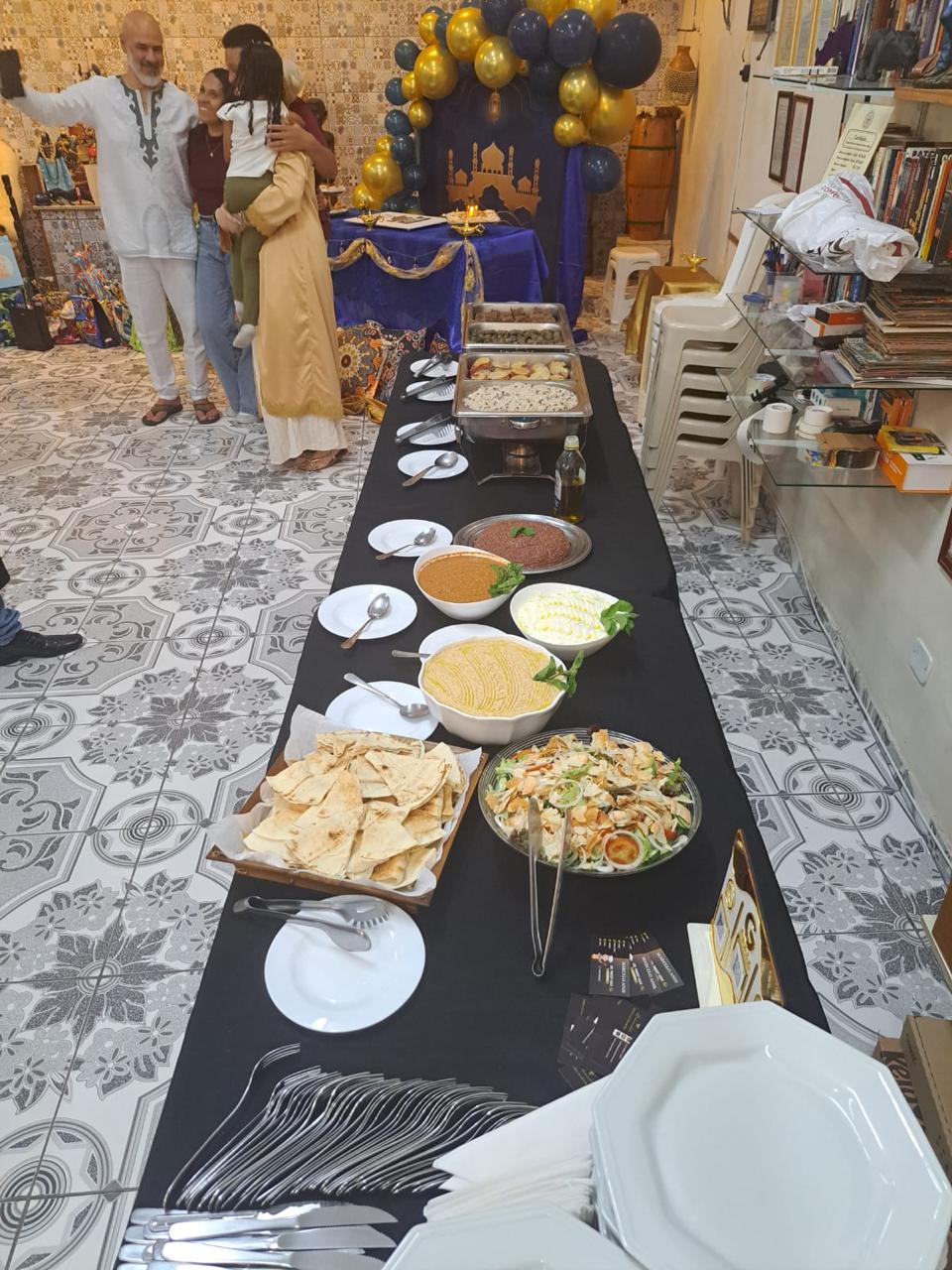 Festa com painel temático árabe, balões dourados e azul-marinho e mesa de buffet